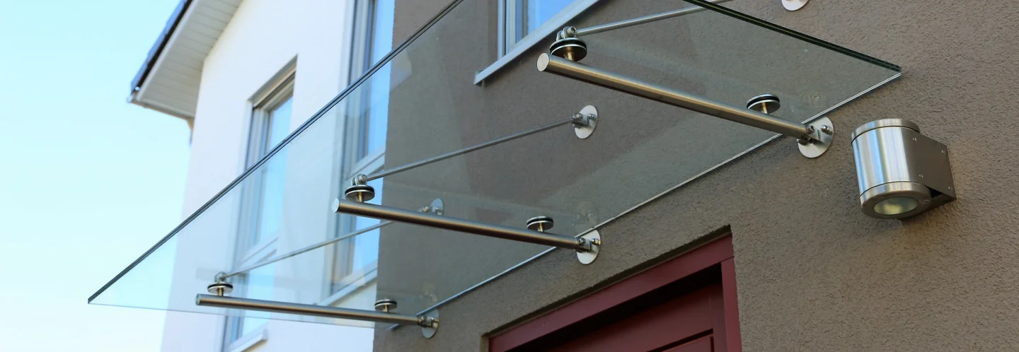 Ein Vordach aus Glas und Metall über einer Tür.